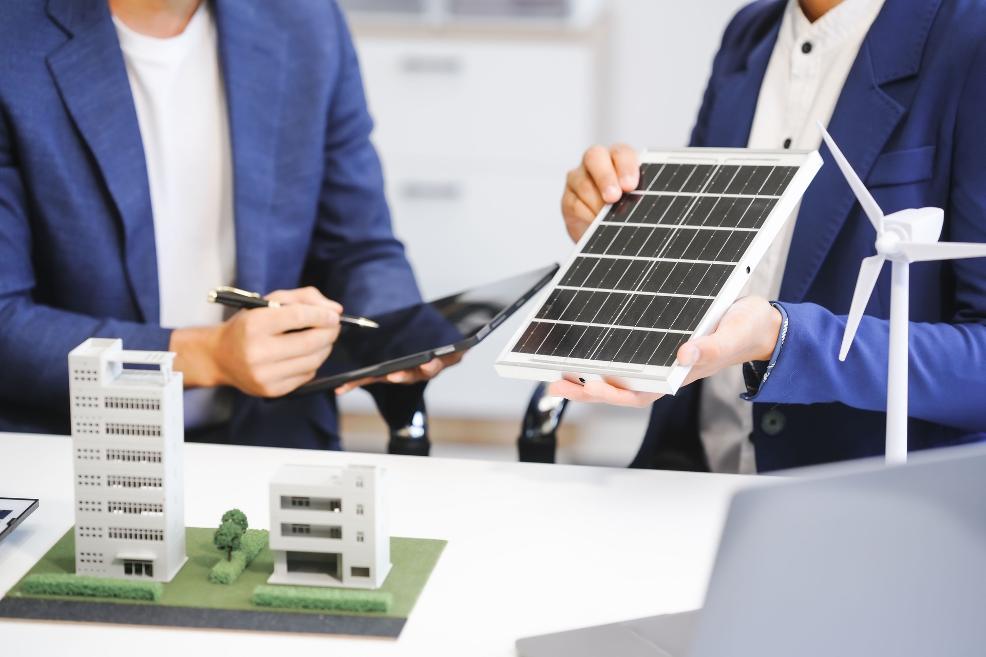 Two Asian businessmen meet at the table with wind power engineers to discuss renewable energy solutions. They exchange ideas on wind turbines, solar energy,simulations for sustainable development